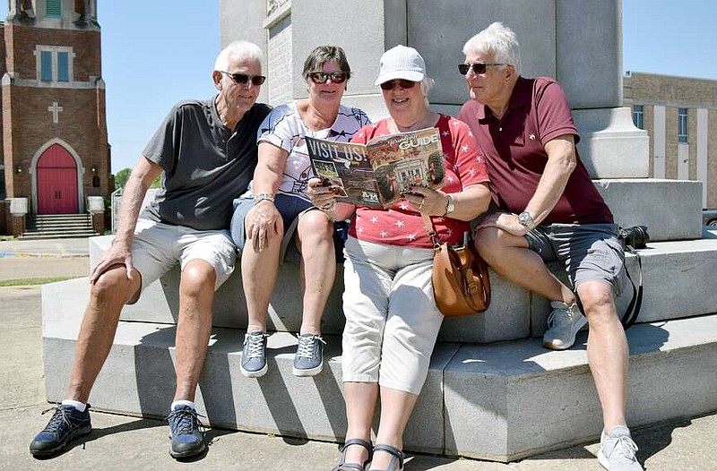 Friends David and Rita Barratt, from left, and Julie and Roger Jarvis peruse a Texarkana city guide during a stop Friday afternoon, April 5, 2024, in downtown Texarkana, Texas. The quartet are from England and are in the U.S. for the solar eclipse. They were traveling through the city on their way to Greenville, Texas, where they plan to experience the eclipse totality. (Staff photo by Stevon Gamble)