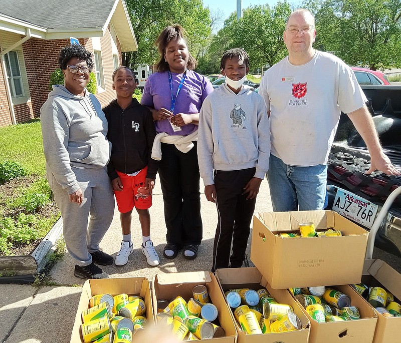 Top, Veronica Bailey, founder and CEO of MMC, gifts children with Easter baskets. Center photo, Bailey, back row, right, and MMC volunteer Brenda Stanley, back row, left, hand out Easter baskets in the parking lot of Johnny B's in El Dorado. Bottom, David Johnson, of the Salvation of Army of El Dorado, receives a donation of approximately 200 canned goods from MMC youth members.