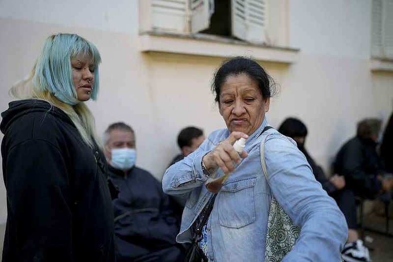 A woman sprays herself with a makeshift mosquito repellant of vanilla and water as she waits to be attended at a hospital amid a surge in dengue fever cases, in Buenos Aires, Argentina, Friday, April 5, 2024. A nationwide increase in dengue fever cases as resulted in the demand for repellents to avoid the bite of the mosquito that transmits the disease, causing a shortage and exorbitant prices where available. (AP Photo/Natacha Pisarenko)