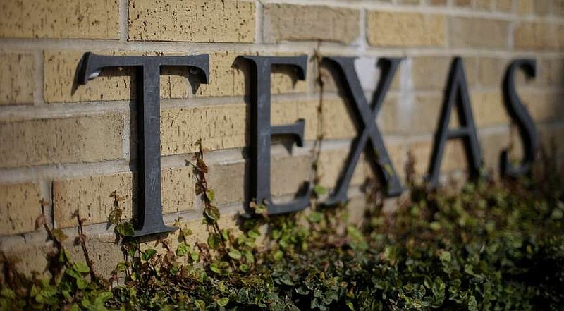 FILE In this Thursday, Nov. 29, 2012 photo, ivy grows near the lettering of an entrance to the University of Texas in Austin, Texas. A group of University of Texas professors is demanding the reversal of job cuts after the 52,000-student campus shut down a program this week to comply with one of the nation's most sweeping bans on diversity, equity and inclusion initiatives.  (AP Photo/Eric Gay)
