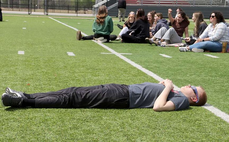 Lynn Kutter/Enterprise-Leader
David Torgerson, a senior at Farmington High, relaxes on Farmington's football field while watching the solar eclipse Monday. Torgerson was born in Farmington, moved to Utah and then moved back to Farmington more than a year ago. The high school released its students and staff to the stadium to observe the eclipse, visit with each other and listen to music blaring from the loud speakers.