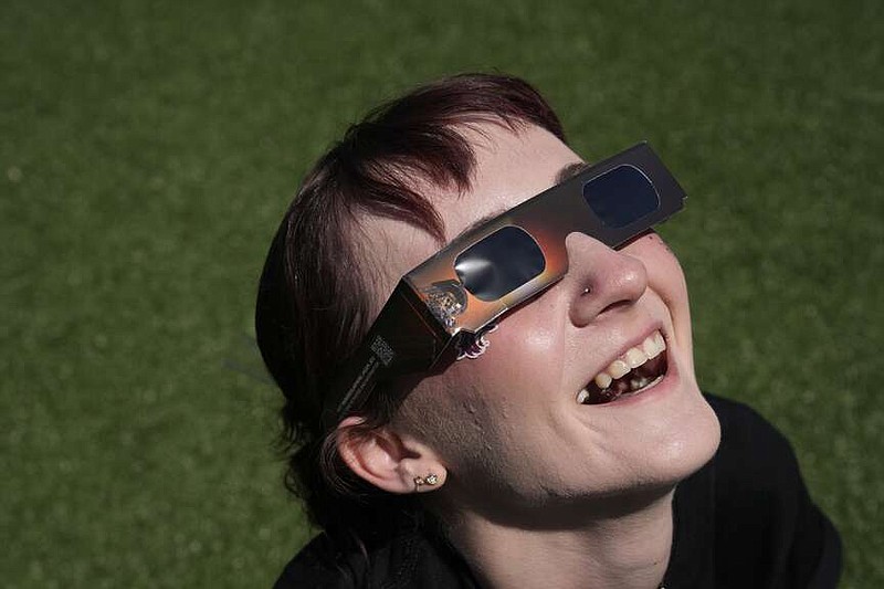 Jordan Elliott smiles as she watches with solar glasses as the moon starts to cross in front of the sun during a total solar eclipse Monday, April 8, 2024, in Carbondale, Ill. (AP Photo/Jeff Roberson)