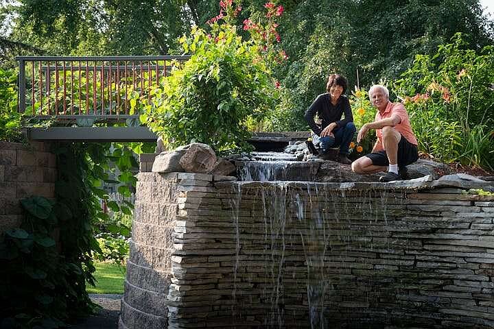 Yee Lee, left, and her husband, Bryan Johnsen, pose for a portrait in the retaining wall feature with a 6-foot waterfall, spiral staircase and bridge that was built by Johnsen. (TNS/Leila Navidi)�