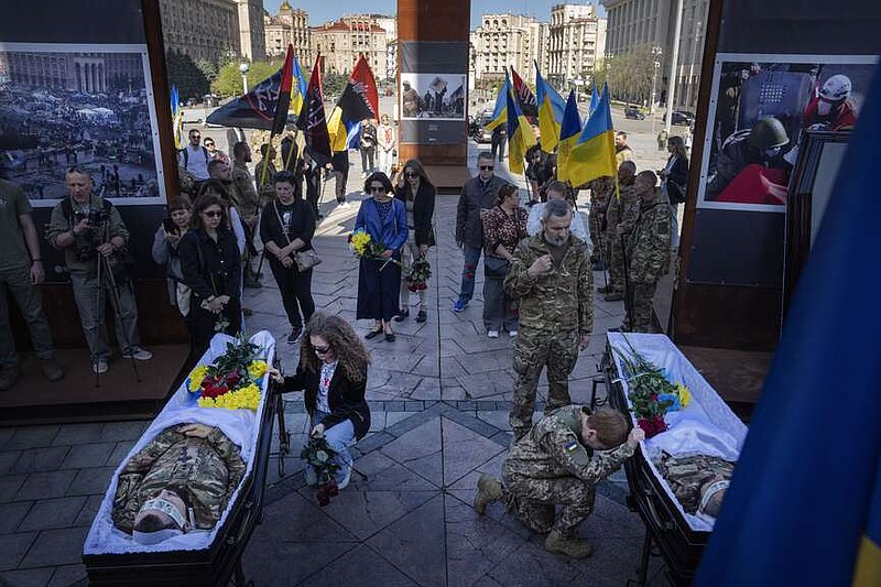 People pay respect at the coffins of Ukrainian servicemen Serhiy Konoval and Taras Petrushun, who were killed in a battle with the Russian troops, during the funeral ceremony in Independence square in Kyiv, Ukraine, Tuesday, April 9, 2024. (AP Photo/Efrem Lukatsky)
