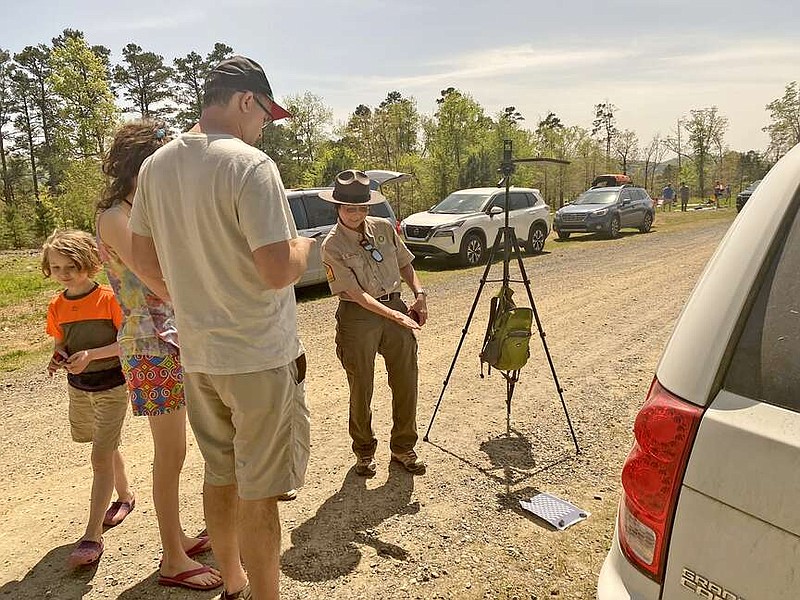 A Lake Ouachita State Park Ranger points out the eclipse as it casts its shadow through a grate Monday. (Submitted photo courtesy of Arkansas State Parks)