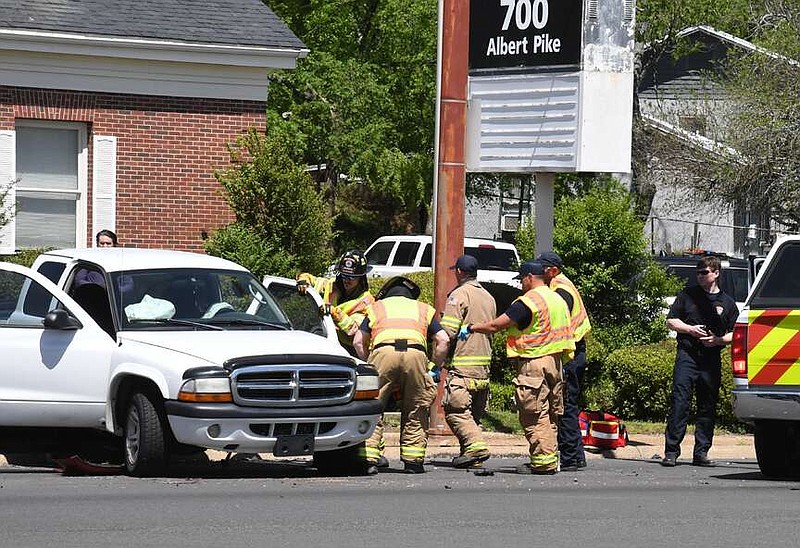 Hot Springs firefighters work on the door of a truck that was involved in a three-vehicle wreck shortly before 12:30 p.m. Thursday on Albert Pike Road at its intersection with Richard Street. (The Sentinel-Record/Lance Brownfield)