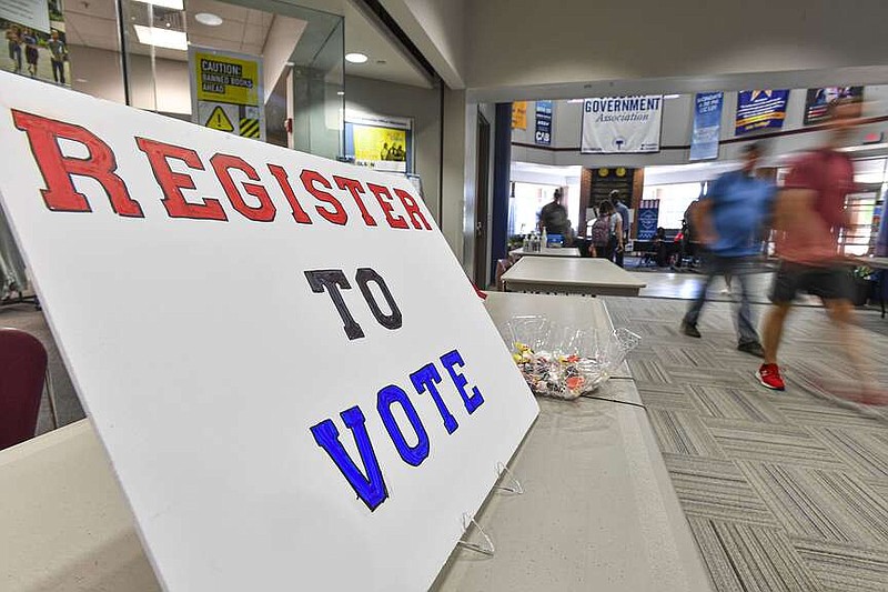 Students at the University of Arkansas-Fort Smith pass a sign encouraging them to register to vote, Tuesday, Sept. 20, 2022, inside the Smith-Pendergraft Campus Center on the UAFS campus in Fort Smith. (NWA Democrat-Gazette/Hank Layton)