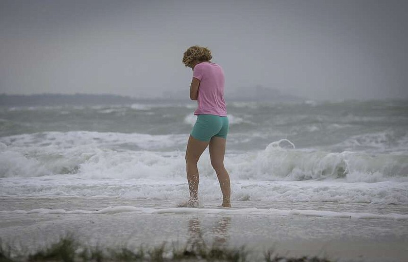 A woman, who asked not to be identified, wades into the water as heavy surf crashes along Main Beach at Honeymoon Island State Park Thursday, April 11, 2024, in Dunedin, Fla. (Chris Urso/Tampa Bay Times via AP)