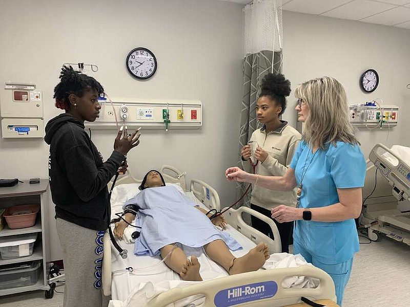 Juniors Jaliyah Brown, left, and Aysia Heard, as well as Health Sciences instructor Kara Gennings, right, treat a robotic patient at Atlanta High School's Career and Technical Education Center on Wednesday, April 10, 2024. “Most of the students here want to do patient care, nursing. Some want to do occupational therapy or dental hygiene,” Gennings said. (Staff photo by Mallory Wyatt)