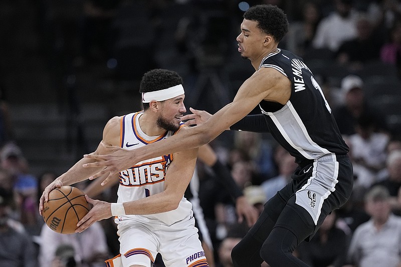 Phoenix Suns guard Devin Booker, left, is defended by San Antonio Spurs center Victor Wembanyama, right, during the second half of an NBA basketball game in San Antonio, Saturday, March 23, 2024. (AP Photo/Eric Gay)