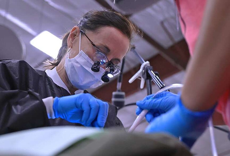 Dr. Syndi Landry-Gray performs a procedure on a patient during the Arkansas Mission of Mercy free dental clinic at the Conway Expo Center in Conway on Saturday, April 13, 2024. (Arkansas Democrat-Gazette/Colin Murphey)