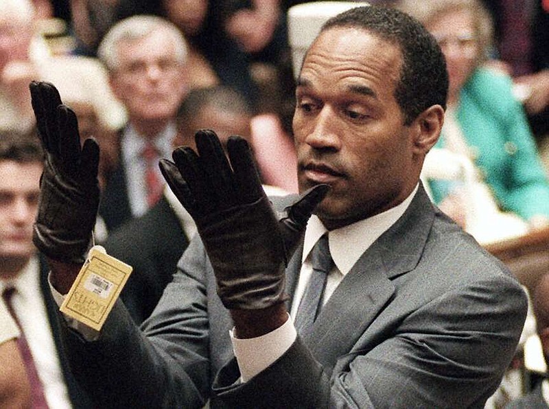 FILE - In this June 21, 1995 file photo, O.J. Simpson holds up his hands before the jury after putting on a new pair of gloves similar to the infamous bloody gloves during his double-murder trial in Los Angeles. Simpson, the decorated football superstar and Hollywood actor who was acquitted of charges he killed his former wife and her friend but later found liable in a separate civil trial, has died. He was 76. (Vince Bucci/Pool Photo via AP, File)