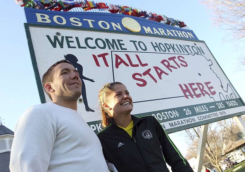 FILE - Jonathon Hawkins, left, and Beth Millian, right, both from Austin, Texas, pose for a photo by the Boston Marathon start sign prior to the 115th running of the Boston Marathon, in Hopkinton, Mass., Monday, April 18, 2011. Once a year for the last 100 years, Hopkinton becomes the center of the running world, thanks to a quirk of geography and history that made it the starting line for the world's oldest and most prestigious annual marathon. (AP Photo/Stew Milne, File)