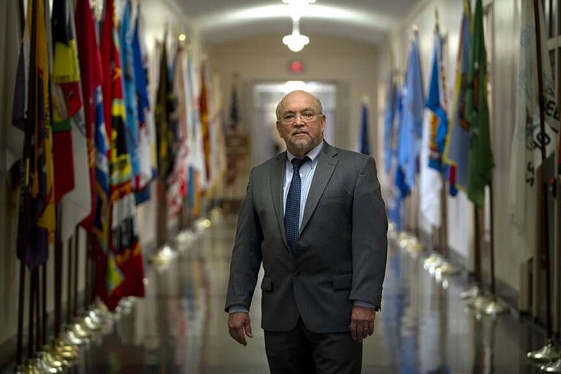 Tracy Toulou, the outgoing Director of the Office of Tribal Justice, stands in a hallway lined with flags of tribal nations at the Department of Justice, Thursday, March 14, 2024, in Washington. For more than two decades, Toulou has confronted the serious public safety challenges facing Indian Country by working to expand the power of tribal justice systems. Today, tribal law enforcement finally has a seat at the table when federal authorities coordinate with state and local police, according to the Justice Department's point person on Native American tribes. (AP Photo/Mark Schiefelbein)