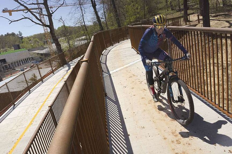 A bike rider passes Thursday along the pedestrian bridge at the one-mile mark for the All-American Mountain Bike Trail in Bentonville. (NWA Democrat-Gazette/Charlie Kaijo)