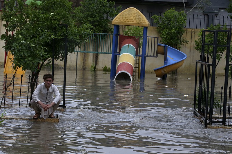 A Pakistani sits beside a flooded park caused by heavy rain in Peshawar, Pakistan, Monday, April 15, 2024. Lightening and heavy rains killed dozens of people, mostly farmers, across Pakistan in the past three days, officials said Monday, as authorities declared a state of emergency in the country's southwest following an overnight rainfall to avoid any further casualties and damages. (AP Photo/Muhammad Sajjad)