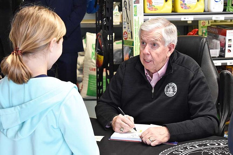 Democrat photo/Garrett Fuller — Gov. Mike Parson, right, speaks with 10-year-old Ava Knoche while signing a copy of his biography, "No Turnin' Back," for her during a signing event Wednesday, April 10, 2024, at Clenin Farm Supply in California. Parson asked Knoche what her favorite subject is in school, and told her his favorite was recess.