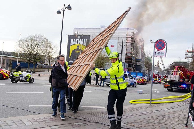 Former Danish Minister of Culture and current CEO of Danish Business, Brian Mikkelsen, left, assists with the evacuation of paintings from the Boersen burning in Copenhagen on Tuesday, April 16, 2024. A fire raged through one of Copenhagen's oldest buildings on Tuesday, causing the collapse of the iconic spire of the 17th-century Old Stock Exchange as passersby rushed to help emergency services save priceless paintings and other valuables.  (Ida Marie Odgaard/Ritzau Scanpix via AP)