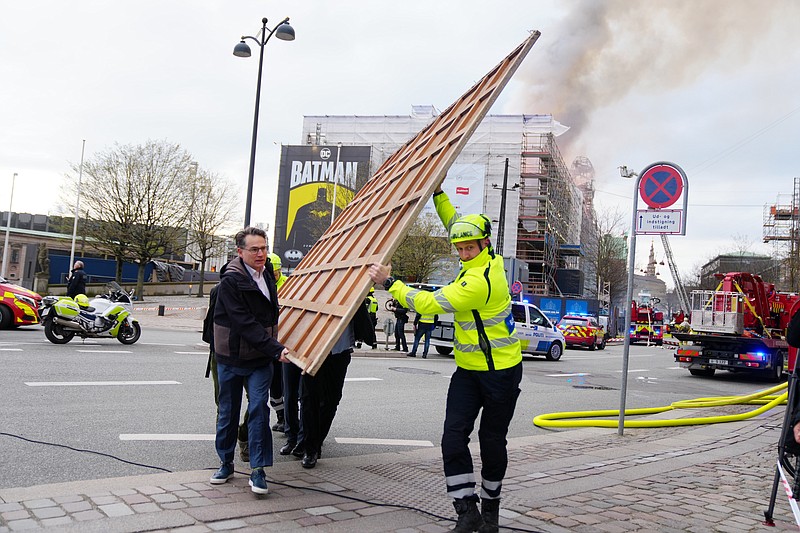 Former Danish Minister of Culture and current CEO of Danish Business, Brian Mikkelsen, left, assists with the evacuation of paintings from the Boersen burning in Copenhagen on Tuesday, April 16, 2024. A fire raged through one of Copenhagen&#x2019;s oldest buildings on Tuesday, causing the collapse of the iconic spire of the 17th-century Old Stock Exchange as passersby rushed to help emergency services save priceless paintings and other valuables.  (Ida Marie Odgaard/Ritzau Scanpix via AP)