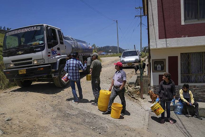 Residents collect water from a truck amid water rationing in La Calera, on the outskirts of Bogota, Colombia, on Tuesday. Amid a drought linked to the El Niño weather pattern, several regions of Colombia have adopted measures to curb water consumption while reservoirs are low. (AP Photo/Fernando Vergara)
