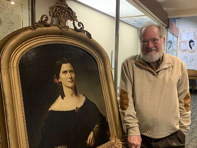 Dr. Thomas W. Cutrer said he has another book in the works, about the life of Texarkana figure Rachel Perry Moores. Pictured is Cutrer at the Texarkana Museum of Regional History, standing next to a portrait of Moores by an unknown artist on Tuesday, April 9, 2024. (Staff photo by Mallory Wyatt)
