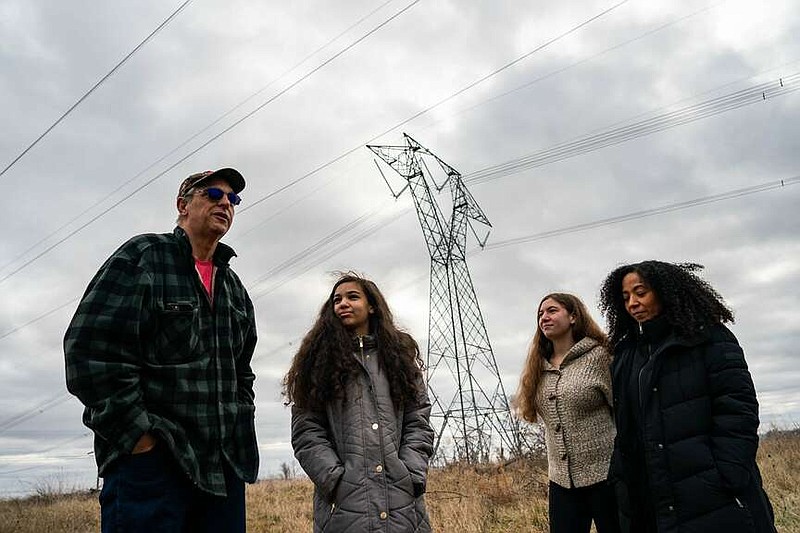 Richard Gee and his wife, Mary, walk along their property with daughters Isabella, 14, and Maria, 16, with transmission lines that abut their land shown behind them in Charles Town, W.Va., in January. MUST CREDIT: Salwan Georges/The Washington Post