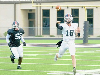 White Hall junior quarterback Wyatt Golden (18) throws a pass while pursued by sophomore defensive lineman Jeremy Drumgoole during the Bulldogs' spring game Thursday. (Special to the Commercial/William Harvey)