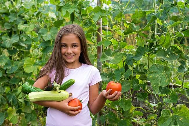 Little girl in vegetable garden - selective focus, copy space