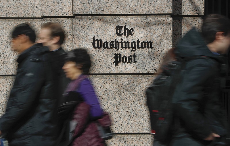 FILE - People walk by the One Franklin Square Building, home of The Washington Post newspaper, in downtown Washington, Feb. 21, 2019. New leaders of The Washington Post are being haunted by their past, with ethical questions raised about their actions as journalists in London that illustrate very different press traditions in the United States and England. (AP Photo/Pablo Martinez Monsivais, File)