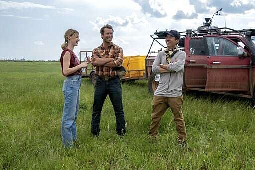 This image released by Universal Pictures shows Daisy Edgar-Jones, left, and Glen Powell, center, with director Lee Isaac Chung on the set of "Twisters." (Melinda Sue Gordon/Universal Pictures via AP)