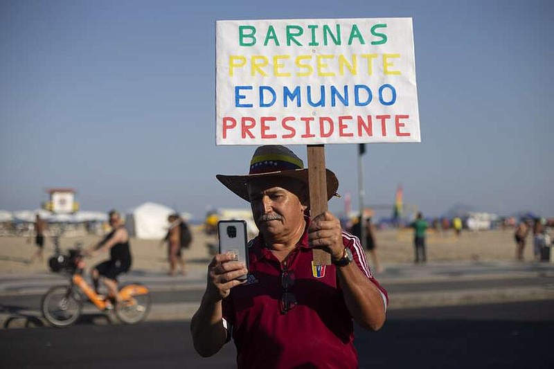 A Venezuelan holds a sign that reads in Spanish: "Barinas present. Edmundo President," during a gathering of Venezuelans in support of opposition presidential candidate Edmundo Gonzalez on the day of the presidential election in Venezuela, on Copacabana beach in Rio de Janeiro, Brazil, Sunday, July 28, 2024. (AP Photo/Bruna Prado)