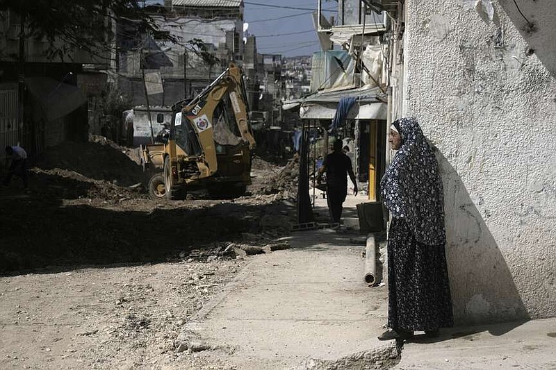 A Palestinian woman watches an operation by the Israeli military in Tulkarem refugee camp in the West Bank, Saturday, Aug. 3, 2024. The Israeli military said it struck five suspected terrorists in a vehicle on their way to carry out an attack. (AP Photo/Majdi Mohammed)