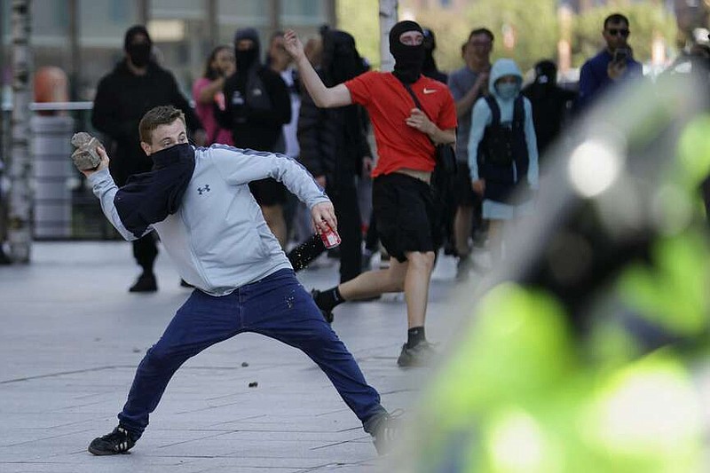 A demonstrator throws a brick during a protest in Liverpool, England, on Saturday, Aug. 3, 2024, following Monday's stabbing attacks in Southport, in which three young children were killed. (James Speakman/PA via AP)