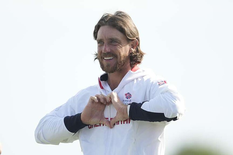 Tommy Fleetwood, of Britain, make a heart sign as he takes his place at the medal ceremony for the men's golf at the 2024 Summer Olympics, Sunday, Aug. 4, 2024, at Le Golf National in Saint-Quentin-en-Yvelines, France. Scottie Scheffler, of the United States, wins the gold medal with Tommy Fleetwood, of Britain, silver and Hideki Matsuyama, of Japan, the bronze.(AP Photo/Matt York)