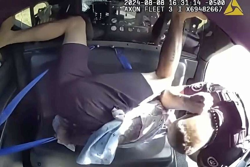 In this image taken from video provided by the Jonesboro, Ark., Police Department, Jonesboro police officer Joseph Harris, right, uses his elbow to strike Billy Lee Coram, who is handcuffed in the back seat of a police car, Thursday, Aug. 8, 2024, in Jonesboro, Ark. (Jonesboro Police Department via AP)