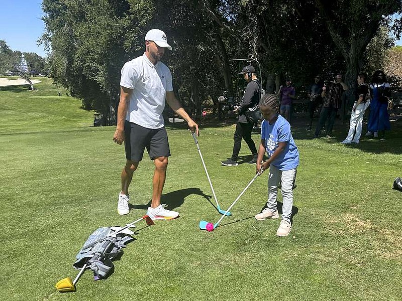 Golden State Warriors' Stephen Curry plays golf with LeAni Wade, 8, a third grader at Oakland's Burckhalter Elementary School at Stanford Golf Course Wednesday, Aug. 28, 2024, in Stanford, Calif. (AP Photo/Janie McCauley)