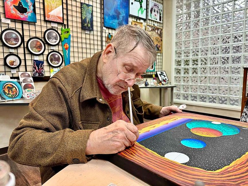 Local artist and Collective Arts Gallery member Jerry Matusky paints an celestial scene at the gallery on Monday. (The Sentinel-Record/Bryan Rice)