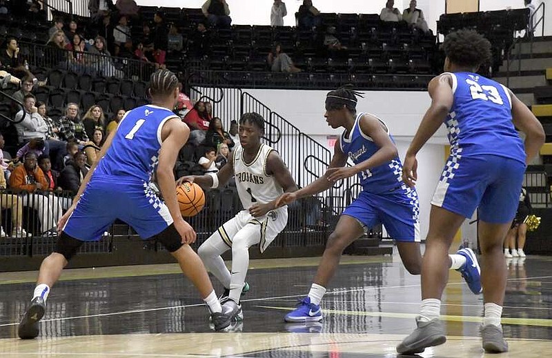 The Trojans' Jaier Hardwell (1) navigates the Hornets' double team Friday night at Trojan Arena. The Trojans fell 85-64. (The Sentinel-Record/Donald Cross)