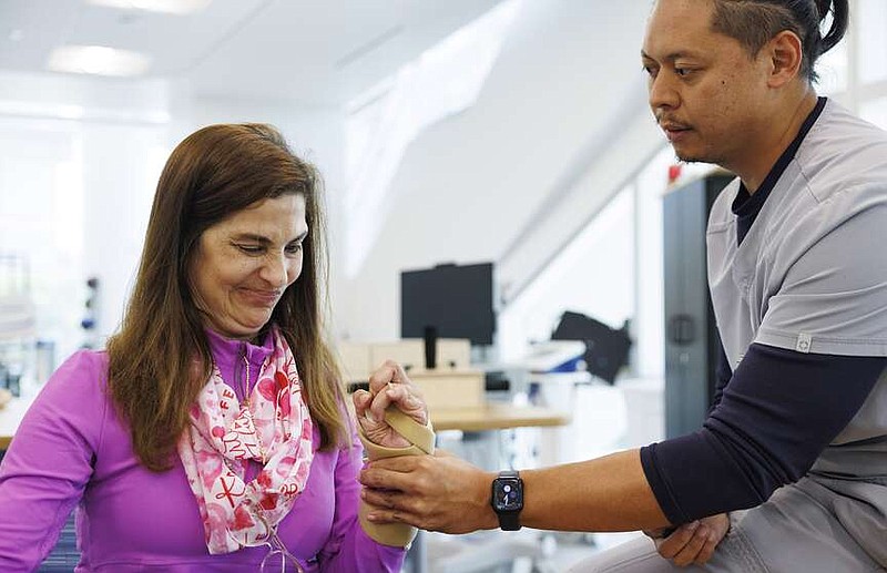 Arlet Lara, the first patient in South Florida to get an FDA-approved nerve stimulation implant, does an exercise where she closes her fist and attempts to reopen it with assistance from Neil Batungbakal, rehabilitation therapist, during her physical therapy appointment on Monday, Sept. 9, 2024, at Lynn Rehabilitation Center at Jackson Memorial Hospital. The implant is designed to help stroke survivors regain function in their arms. (Alie Skowronski/Miami Herald/TNS)