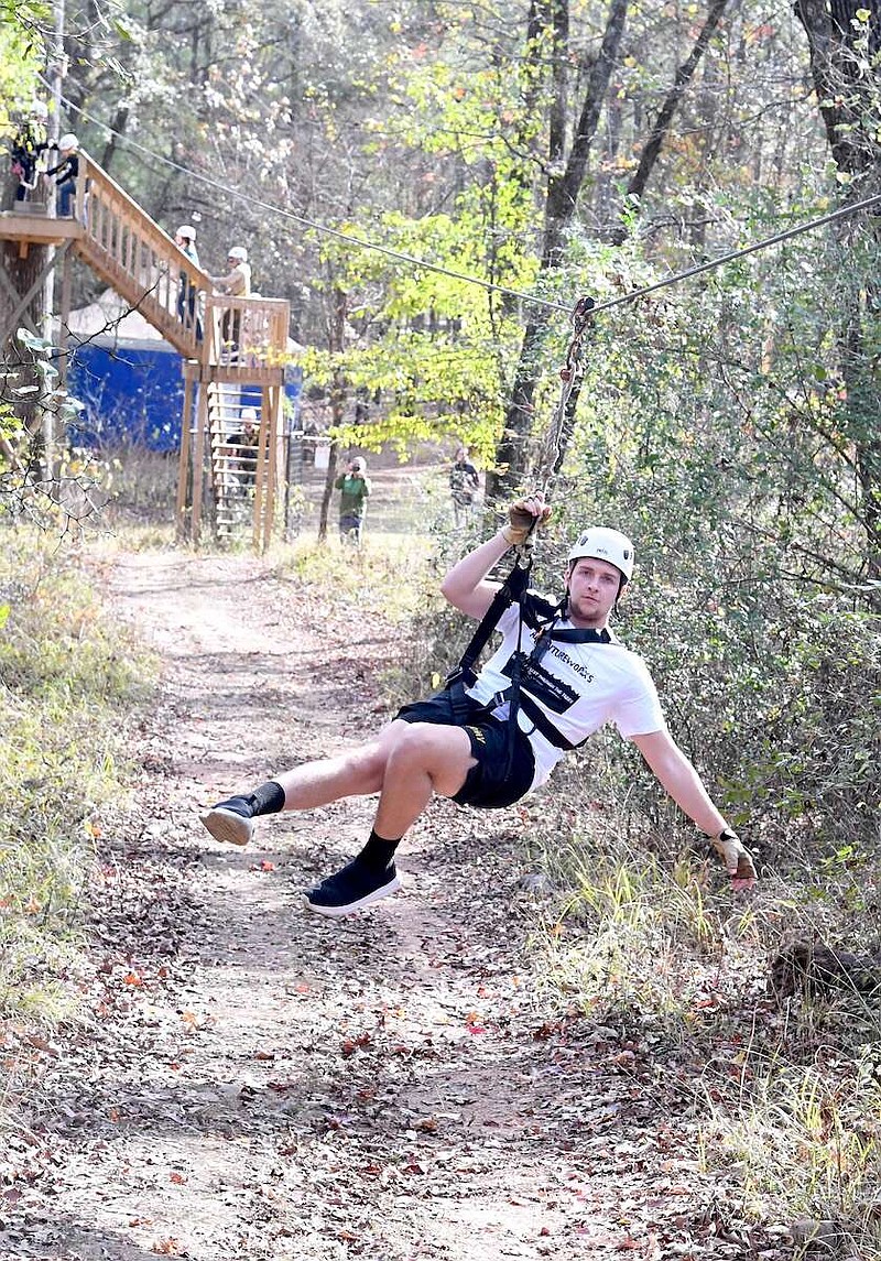 A tour guide at Adventureworks speeds down a zip line. The zip line course is holding its first Holly Jolly Zipline Tour through Dec. 23. (The Sentinel-Record/Donald Cross)