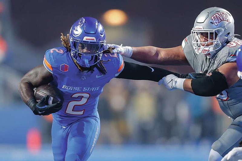 Boise State running back Ashton Jeanty (2) pushes away from the arms of UNLV defensive lineman Tatuo Martinson (98) on a run in the first half of the Mountain West Championship NCAA college football game Friday, Dec. 6, 2024, in Boise, Idaho. (AP Photo/Steve Conner)