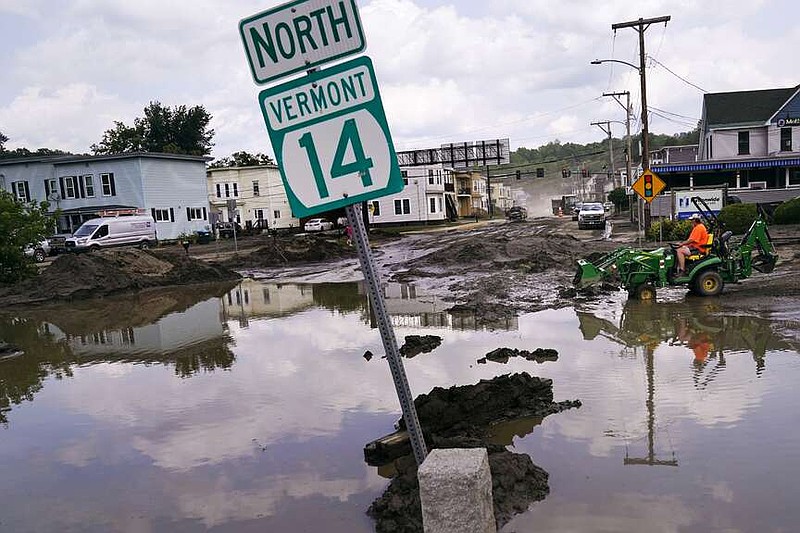 A small tractor clears water from a business as flood waters block a street July 12, 2023, in Barre, Vt. (AP Photo/Charles Krupa, File)