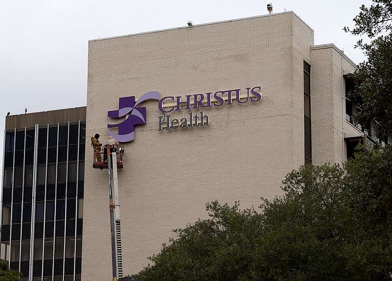 Two employees of Rainbow Signs, of Louisiana, install the CHRISTUS Health sign on the hospital system's Pine Street campus, formerly known as Wadley Regional Medical Center, on Saturday afternoon, Jan. 4, 2025, in Texarkana, Texas. CHRISTUS Health, an international, not-for-profit Catholic health system, finalized its purchase of Wadley on Nov. 1, 2024. A federal bankruptcy judge in Texas approved the sale in September. Wadley's previous owner, Steward Health Care, offloaded the hospital as part of company-wide financial restructuring. (Staff photo by Stevon Gamble)