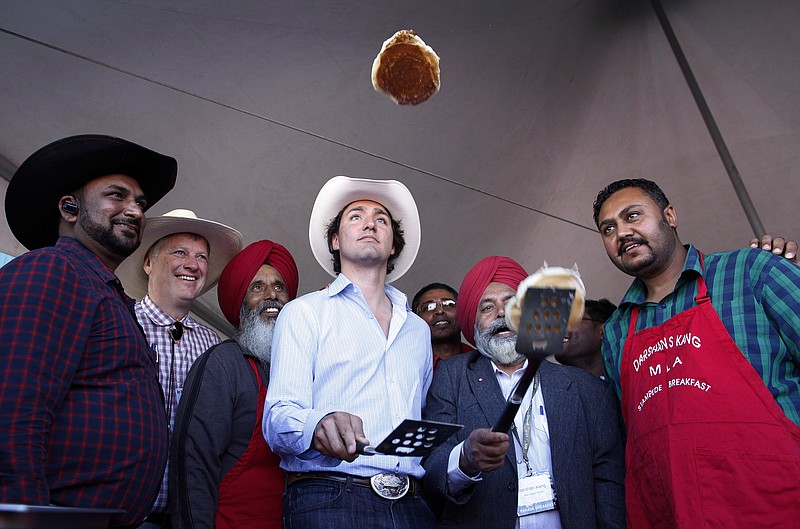 FILE - Liberal leader Justin Trudeau, center, flips pancakes at a Stampede breakfast in Calgary, Alta., on July 7, 2013. (Jeff McIntosh/The Canadian Press via AP, File)