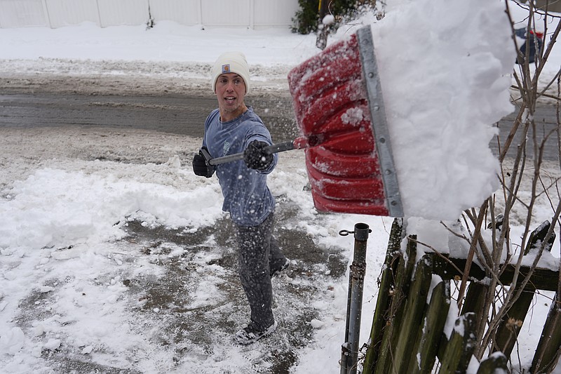 Ben Sisarsky pitches snow over a fence as he clears his girlfriend's parking spot with a borrowed snow shovel in Cincinnati, Tuesday, Jan. 7, 2025. (AP Photo/Carolyn Kaster)