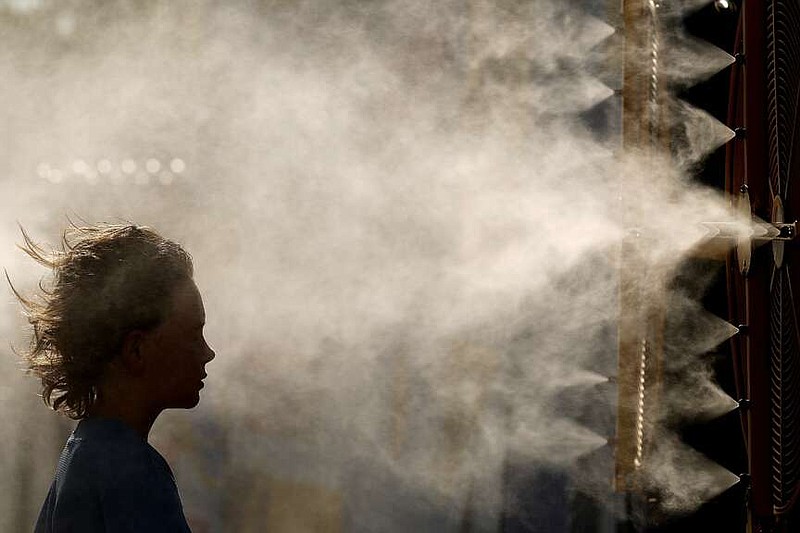 Michael Mullenax, 10, from Lee's Summit, Mo., cools off in a mister at Kauffman Stadium before a baseball game between the Kansas City Royals and the Miami Marlins on June 24, 2024, in Kansas City, Mo. (AP Photo/Charlie Riedel, File)