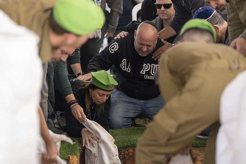 Gali and Nir, the parents of Israeli soldier Sergeant Yahav Maayan who was killed in combat in the Gaza Strip, react next to his grave during his funeral at a military cemetery in Modiin, Israel, Sunday, Jan. 12, 2025. (AP Photo/Ohad Zwigenberg)