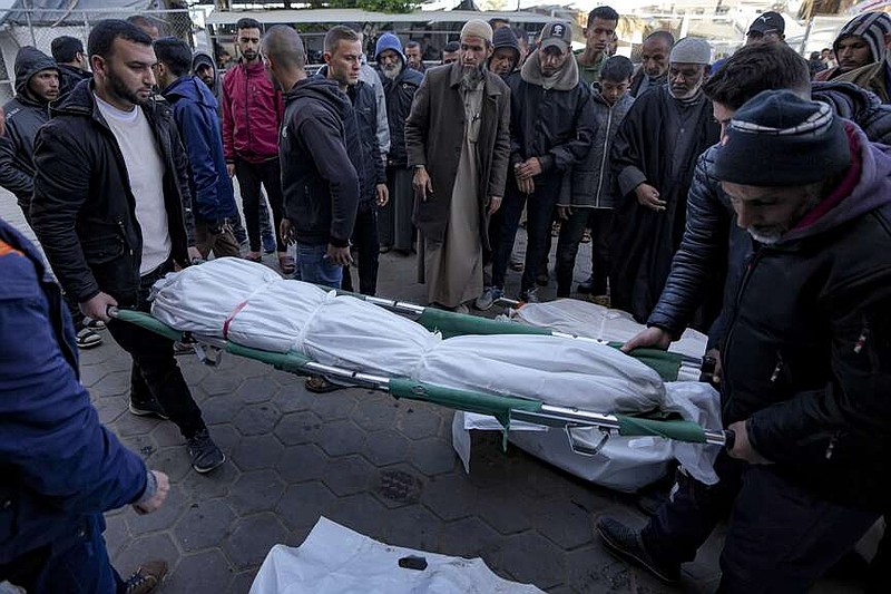 Palestinians carry the body of a relative killed in the Israeli bombardment of the Gaza Strip at Al-Aqsa Hospital in Deir Al-Balah, Tuesday, Jan. 14, 2025. (AP Photo/Abdel Kareem Hana)