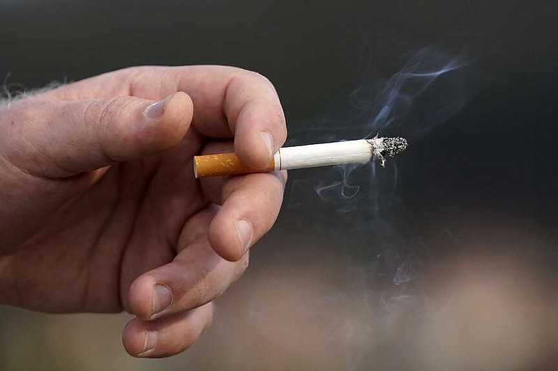 FILE - A man holds a lit cigarette while smoking Dec. 2, 2020, in San Francisco. (AP Photo/Jeff Chiu, File)