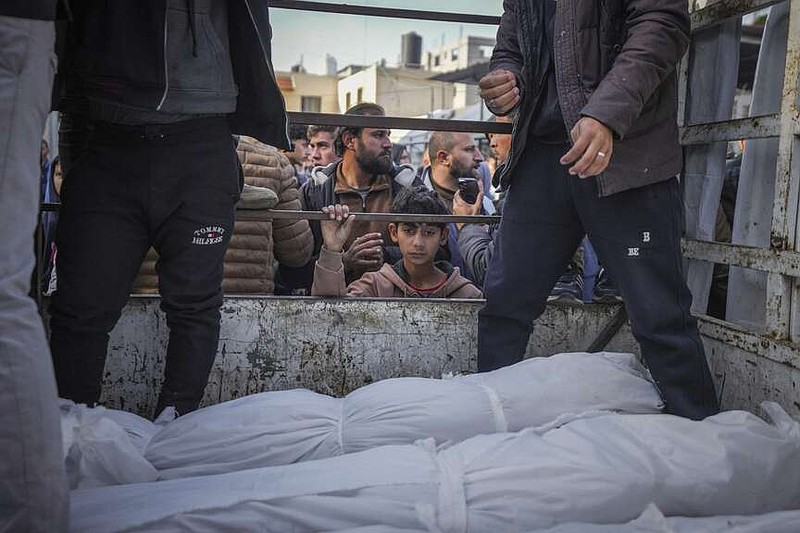 A boy looks at the bodies of Palestinians killed in the Israeli bombardment of the Gaza Strip as they are brought for burial at Al-Aqsa Hospital in Deir al-Balah, Wednesday, Jan. 15, 2025. (AP Photo/Abdel Kareem Hana)